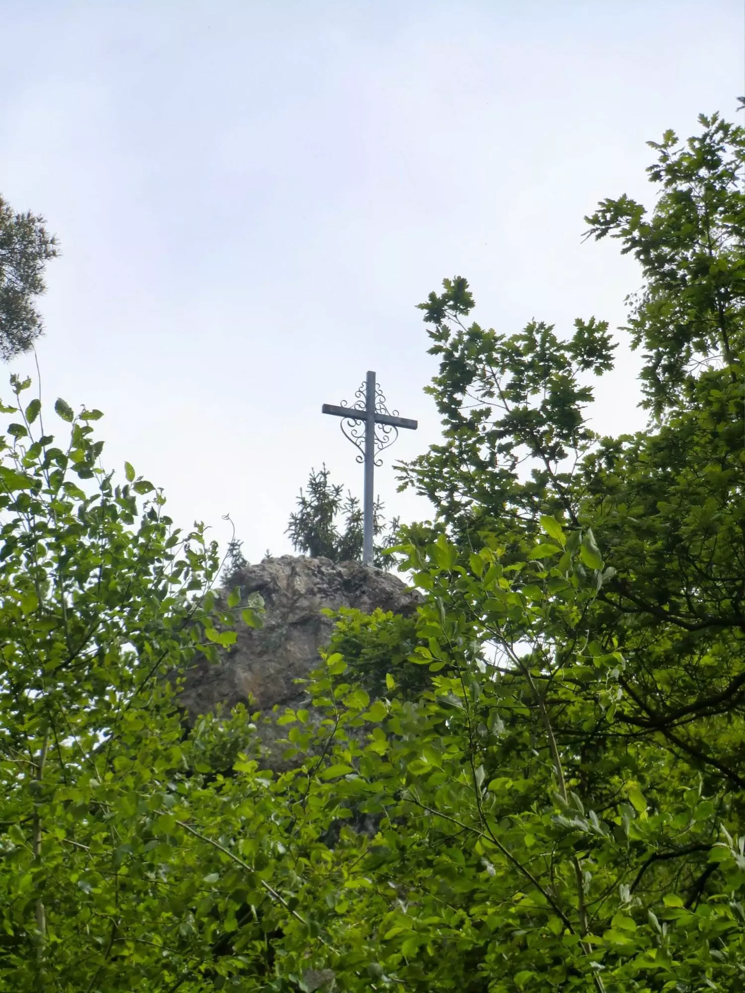 Eine Wanderung im Taunus führt zu einem Kreuz auf einem Hügel, umgeben von Bäumen.