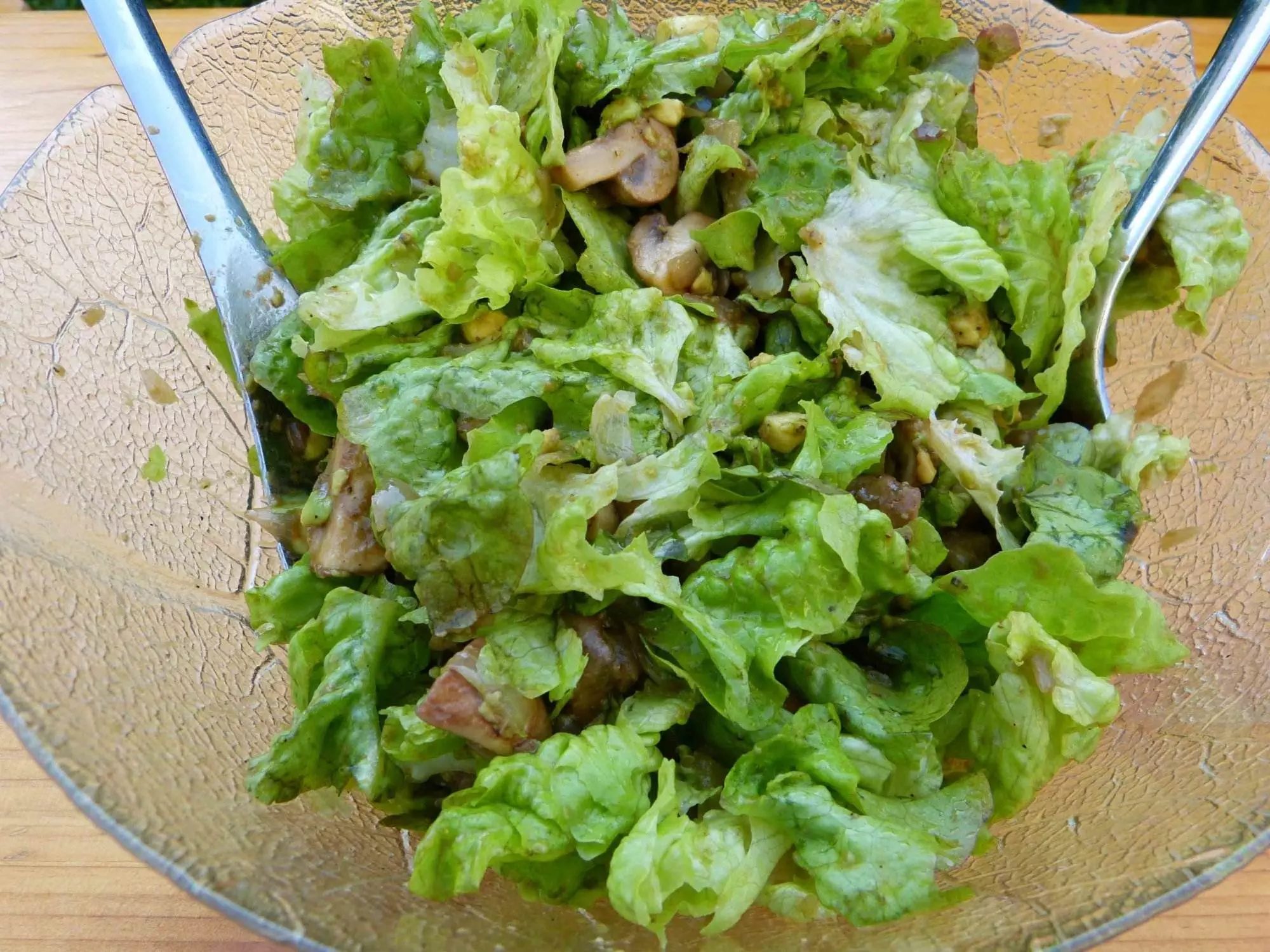 Ein Salat mit Champignons, serviert in einer Schüssel mit zwei Gabeln.