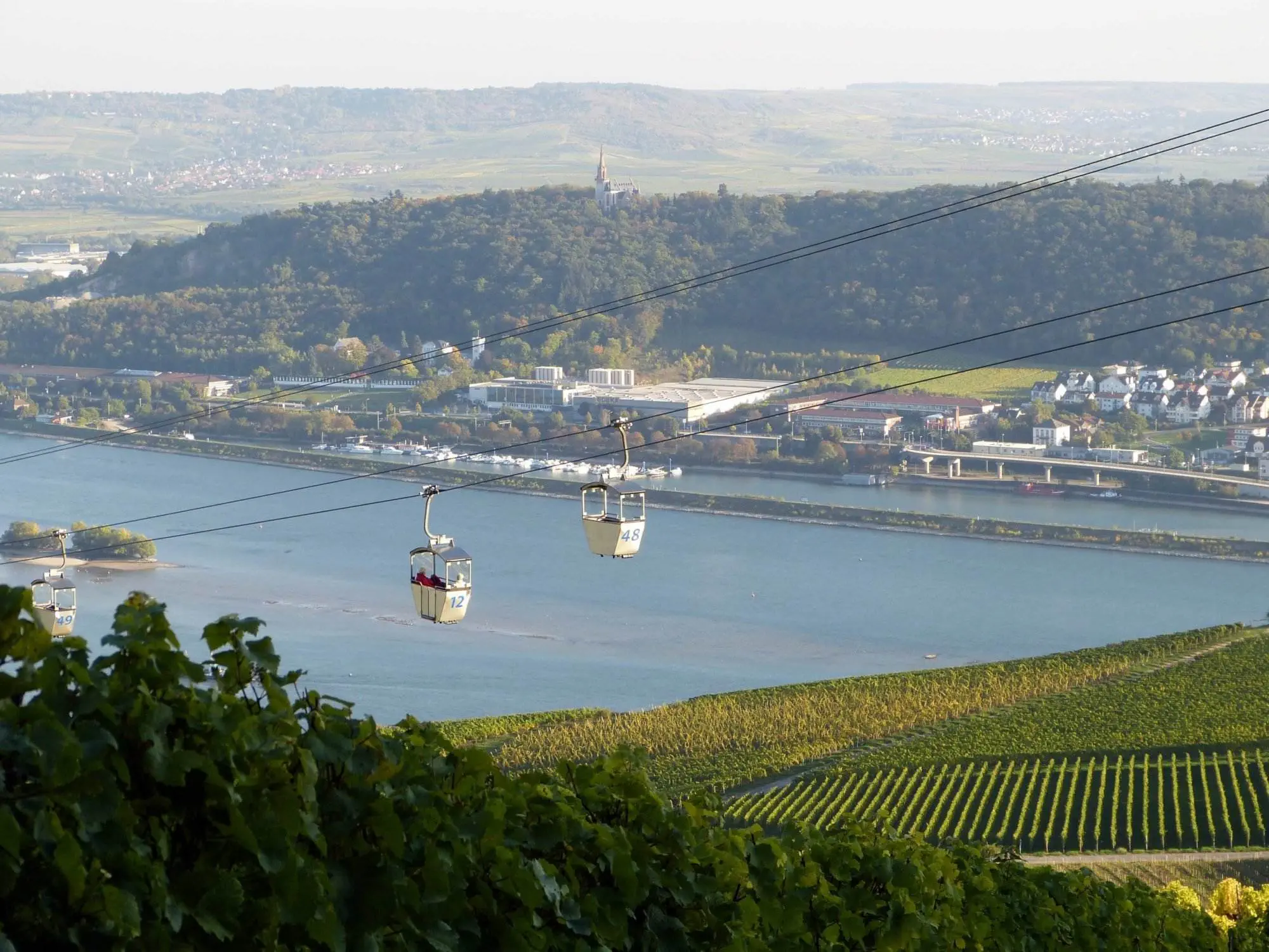 Eine malerische Rheinsteig-Wanderung enthüllt eine Seilbahn mit Blick auf einen Fluss und Weinberge.