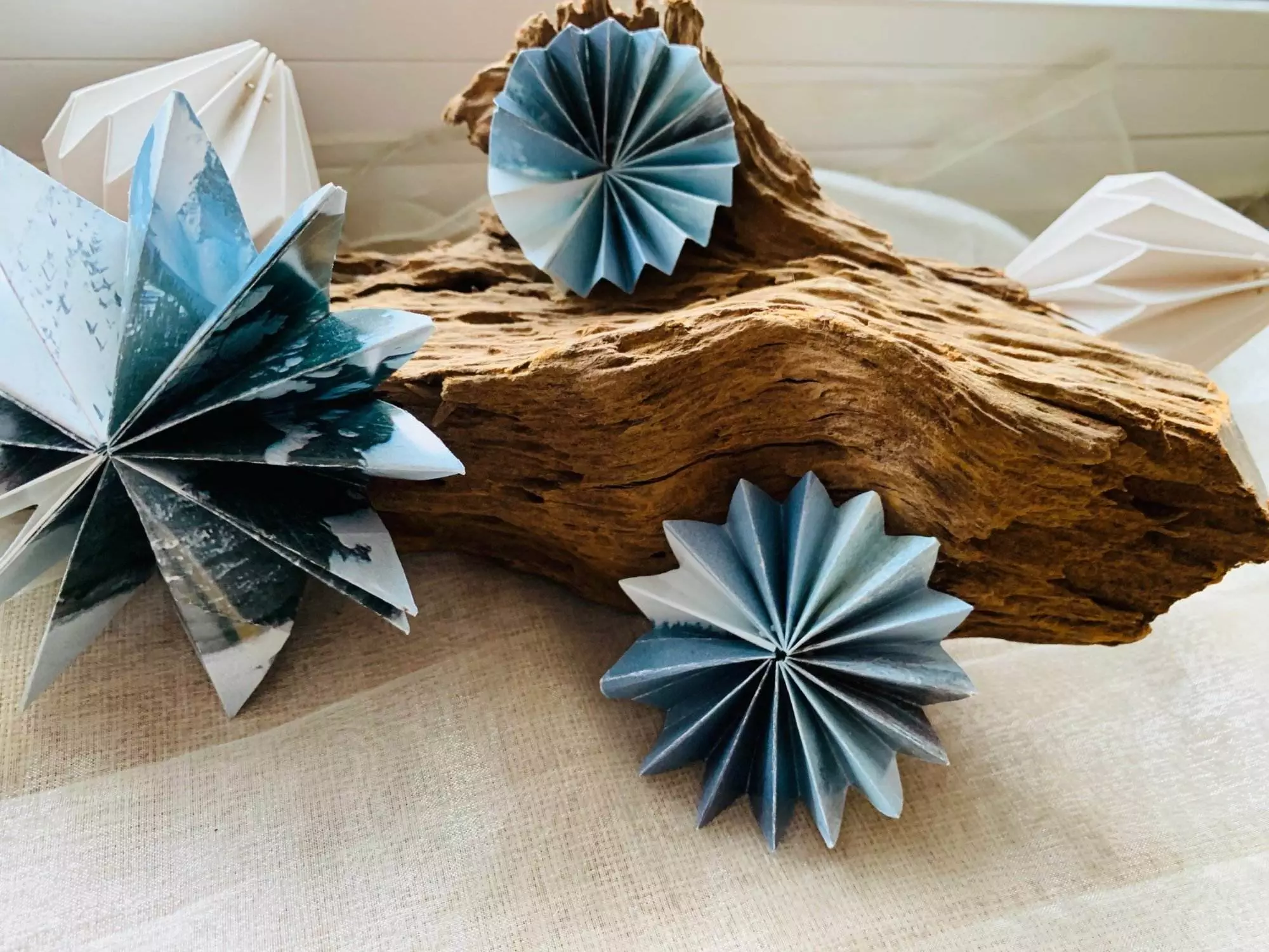 Drei Origami-Sterne auf einem Stück Holz.