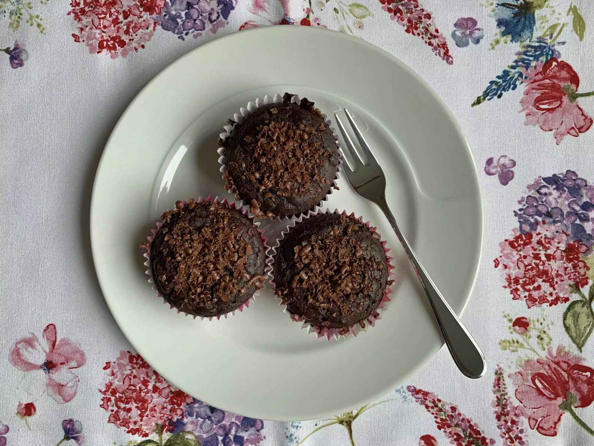 Drei Schokoladen-Cupcakes auf einem Teller mit einer Gabel.