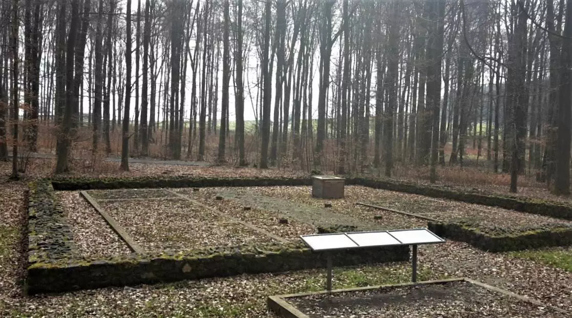 Ein Friedhof in einem Waldgebiet mit einem Schild.
