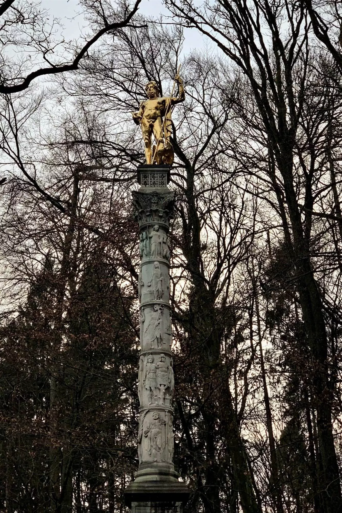 Eine Statue steht auf einer Säule in einem Park.