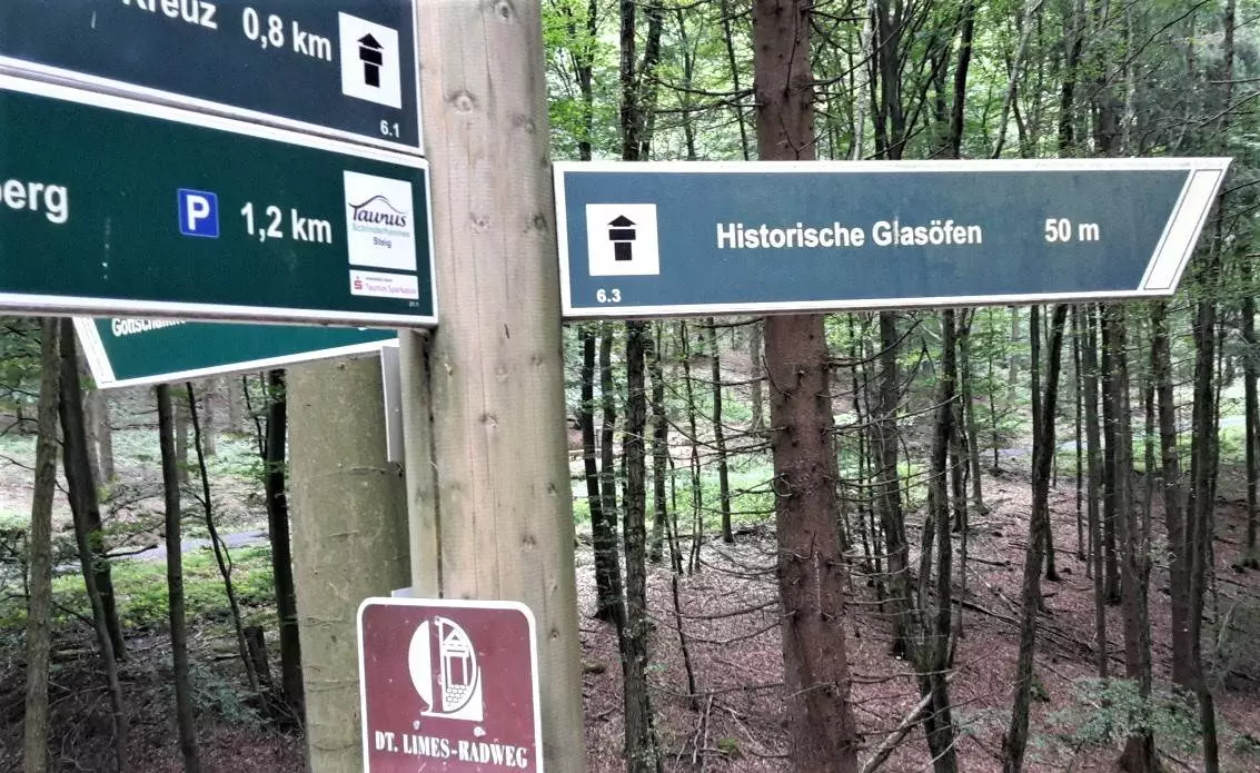 Ein Schild im Wald mit mehreren verschiedenen Richtungen.